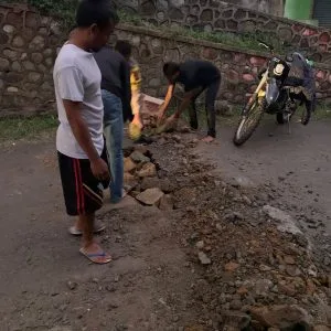 Bhabinkamtibmas Lakukan Pembenahan Jalan Raya Yang Berlubang Karena Dilintasi Warga Sebagai Wujub Kemitraan